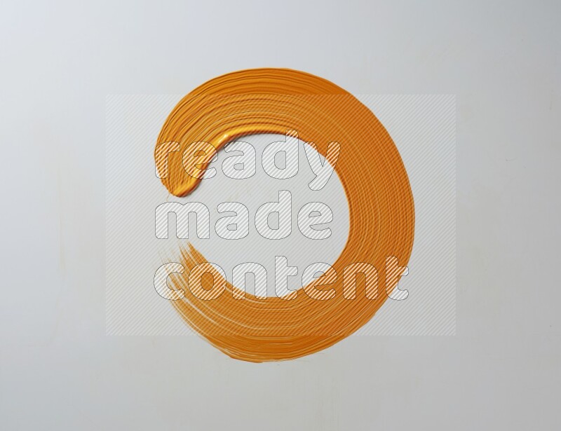 An orange circular painting brush stroke on white background