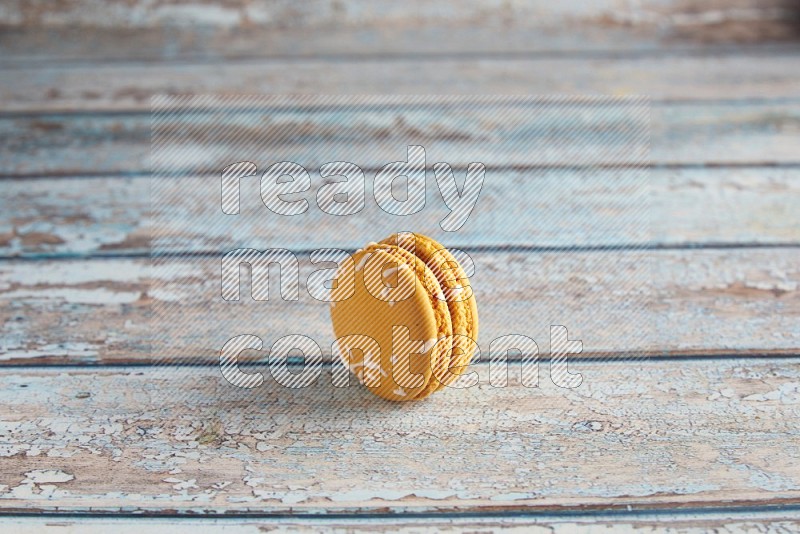 45º Shot of Yellow Piña Colada macaron on light blue wooden background