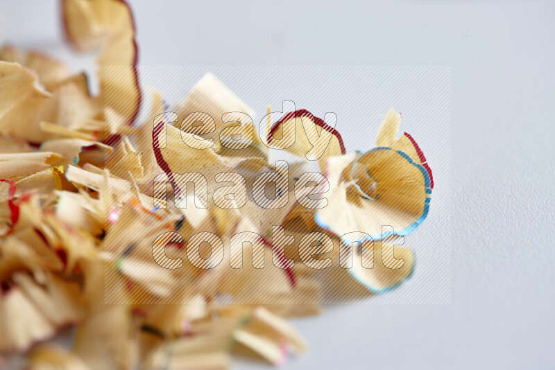 A close-up showing a small pile of pencil shavings with varied color edges on grey background