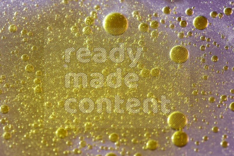 لقطات مقربة لقطرات ألوان مائية صفراء على سطح الزيت على خلفية وردية