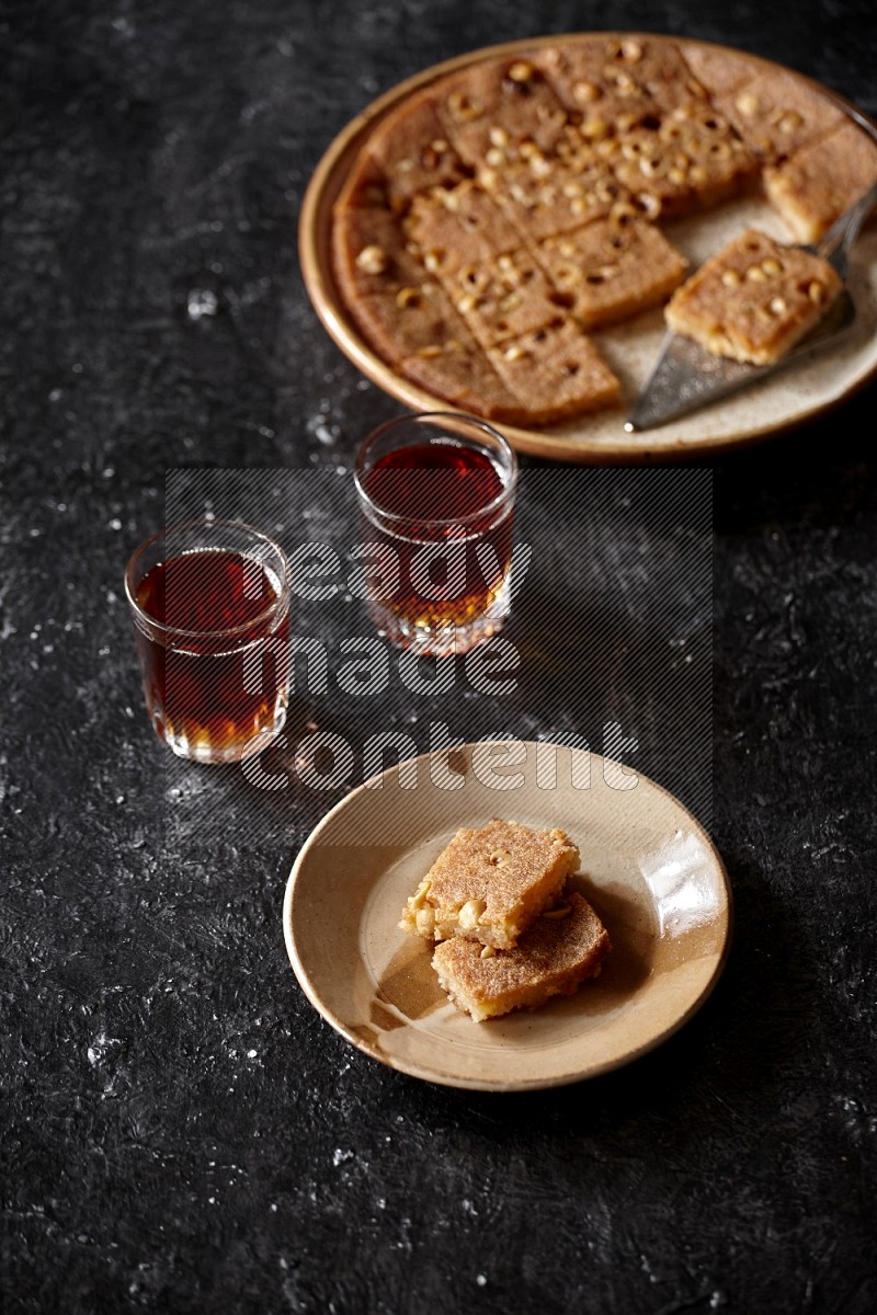 Basbousa with tea in a dark setup