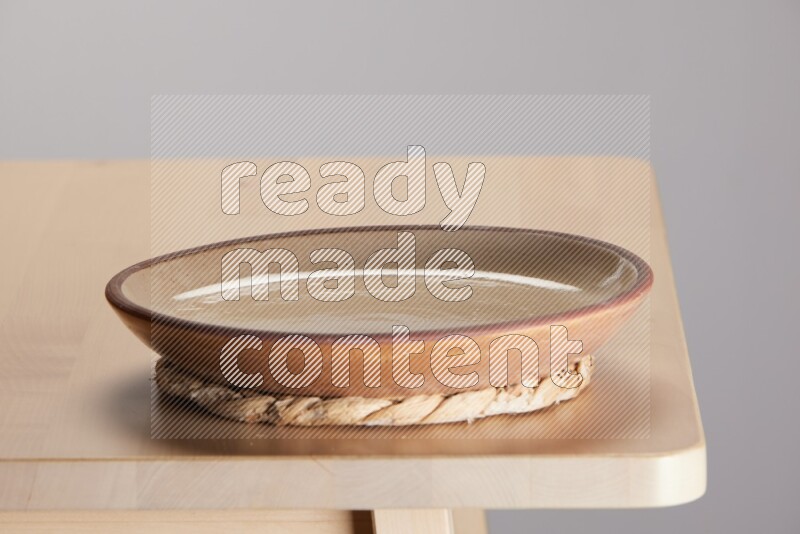 multi-colored pottery Plate placed on a small light colored straw placemat on the edge of wooden table