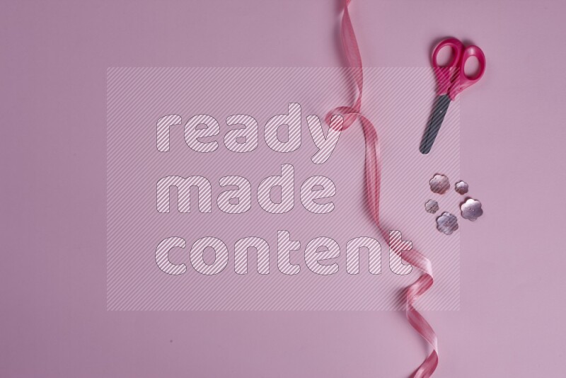 A pink collection of sewing and tailoring tools arranged on a pink background