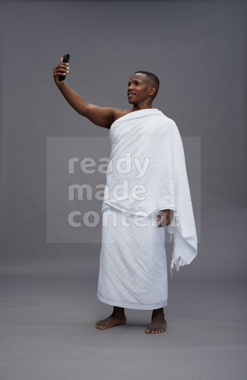 A man wearing Ehram Standing taking selfie on gray background