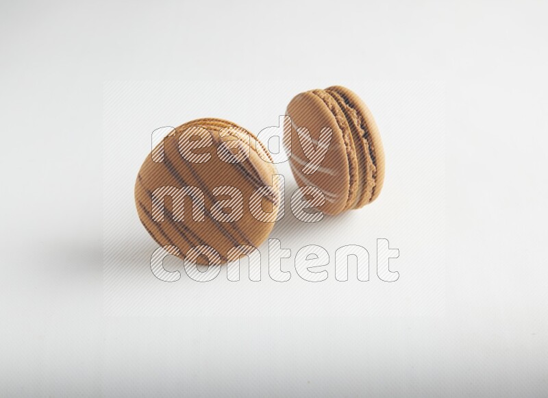 45º Shot of of two assorted Brown Irish Cream, and light brown  Almond Cream macarons on white background