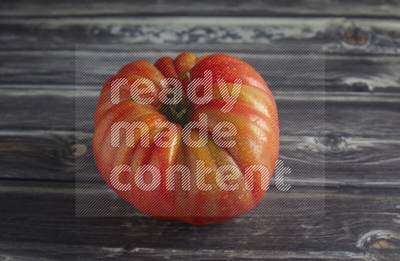 45 degree single heirloom tomato on a textured grey wooden background