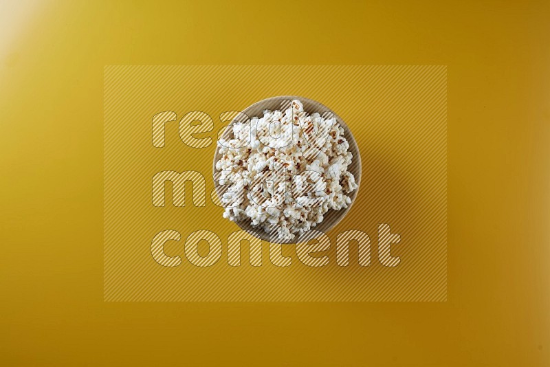 A multicolored ceramic plate full of popcorn on a yellow background in different angles