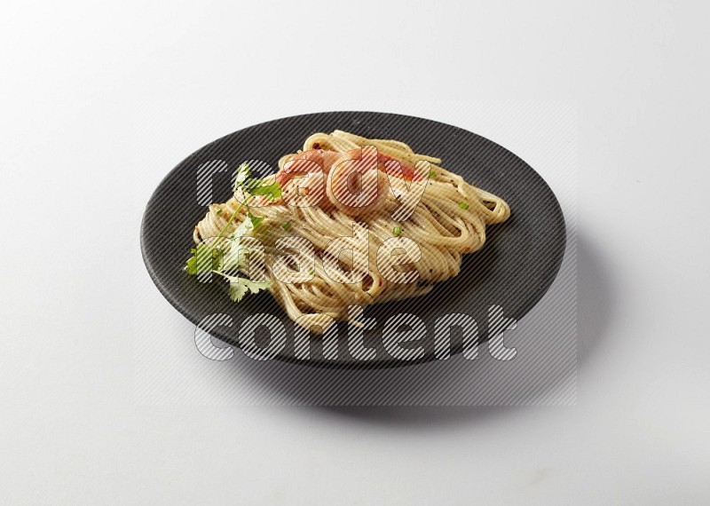 spaghetti pasta with white sauce on a black plate on a white background