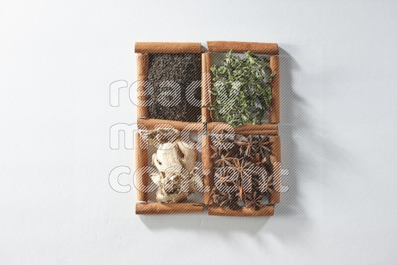 4 مربعات من أعواد القرفة ممتلئة بالشاي والنعناع واليانسون والزنجبيل على أرضية بيضاء