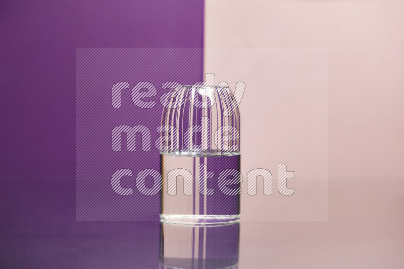 The image features a clear glassware filled with water, set against purple and rose background