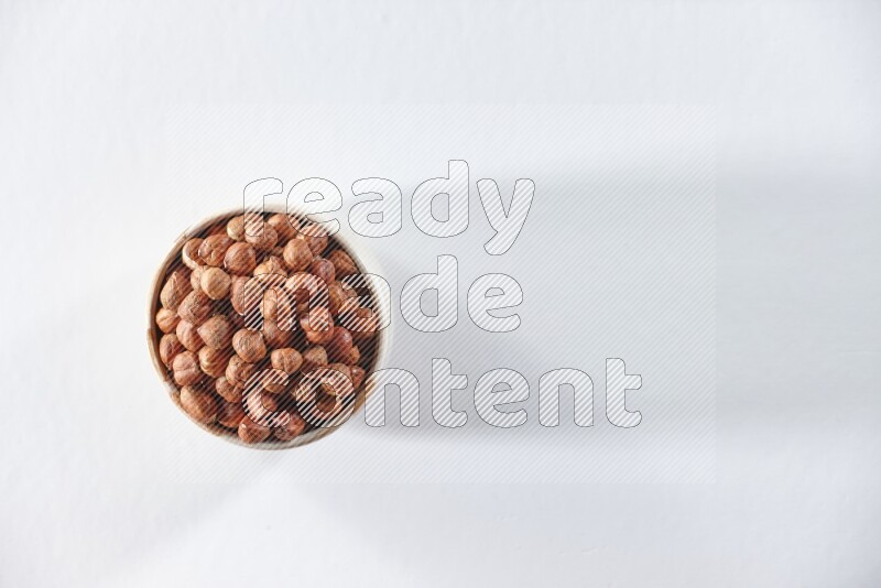 A beige ceramic bowl full of peeled hazelnuts on a white background in different angles