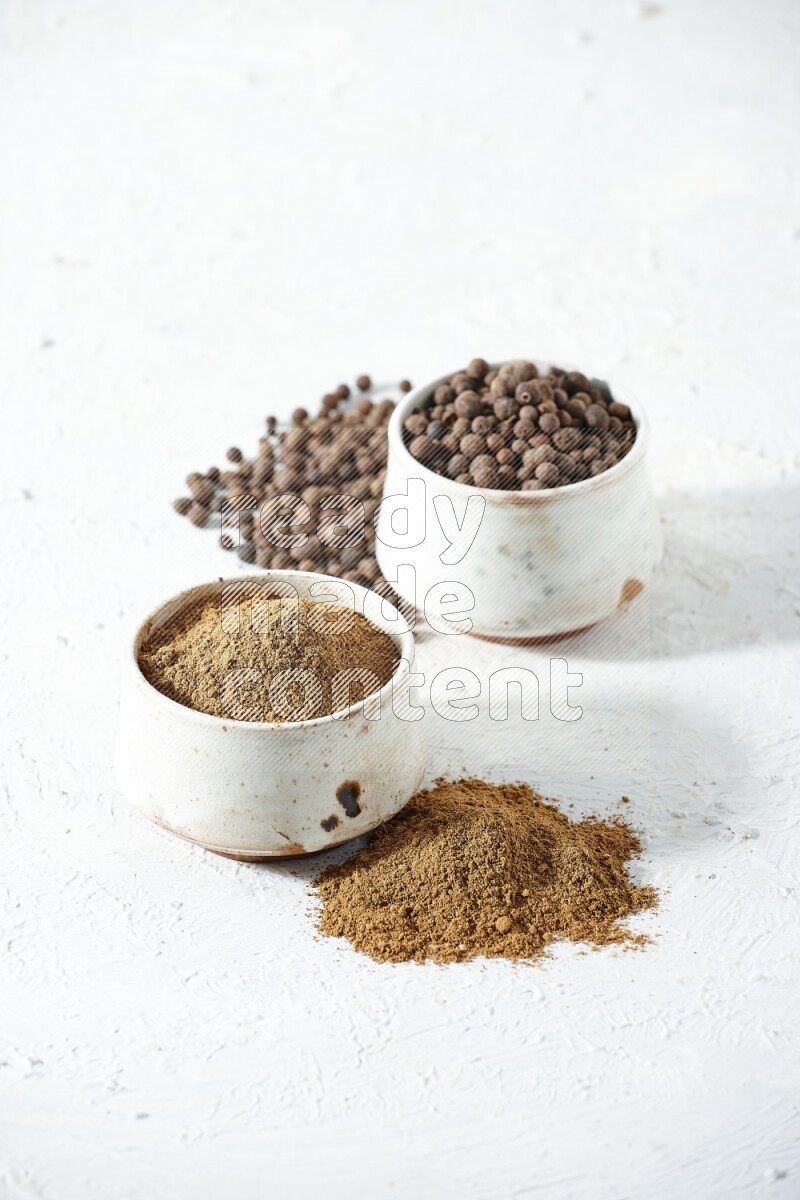 وعاءان بيج، أحدهما ممتلئ ببودرة بهار الفلفل الحلو والآخر بالحبوب مع البودرة والحبوب متناثرة على خلفية بيضاء