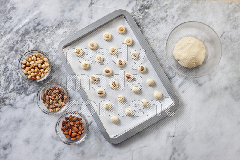 Ghoriba step by step with its ingredient, flour, powdered sugar, ghee and nuts on grey marble background