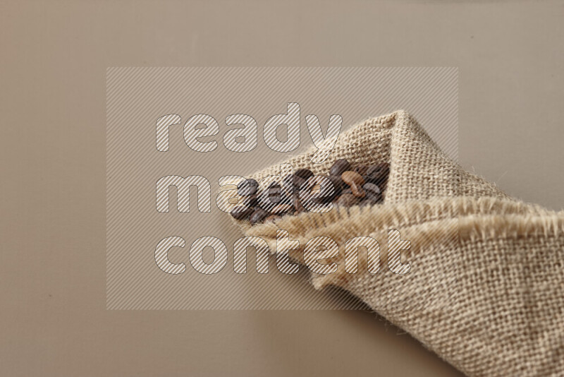 Spilled roasted coffee beans from its pack on beige background