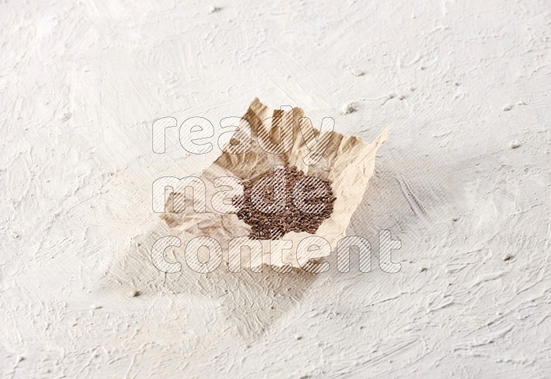 حبوب بذر الكتان في قطعة من الورق علي خلفية بيضاء