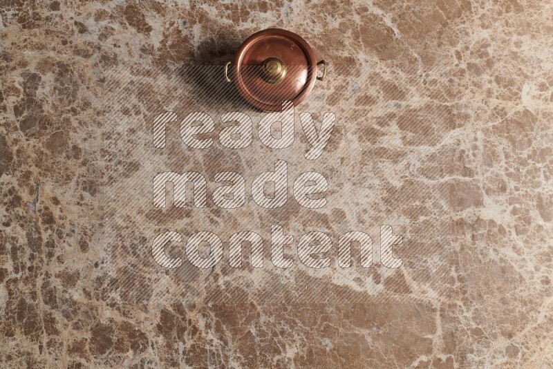 A small copper pot on beige marble background