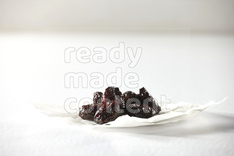 Dried plums on a crumpled piece of paper on a white background in different angles