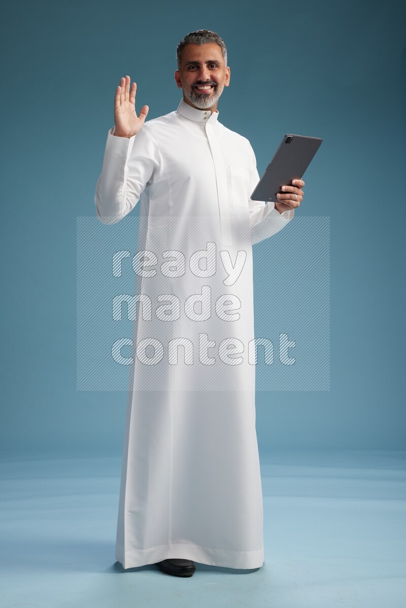 Saudi man waring thob with tablet on blue background