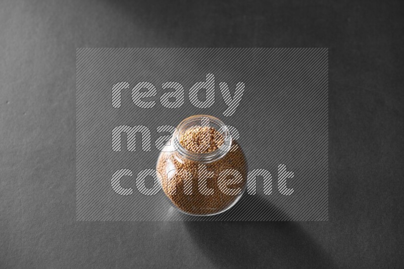 حبوب الخردل في وعاء زجاجي علي خلفية سوداء