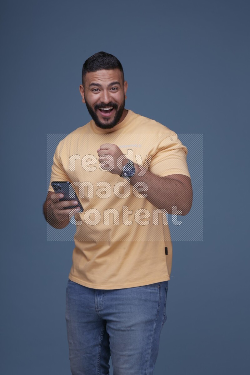 A man Texting on his phone in Blue Background wearing Orange T-shirt
