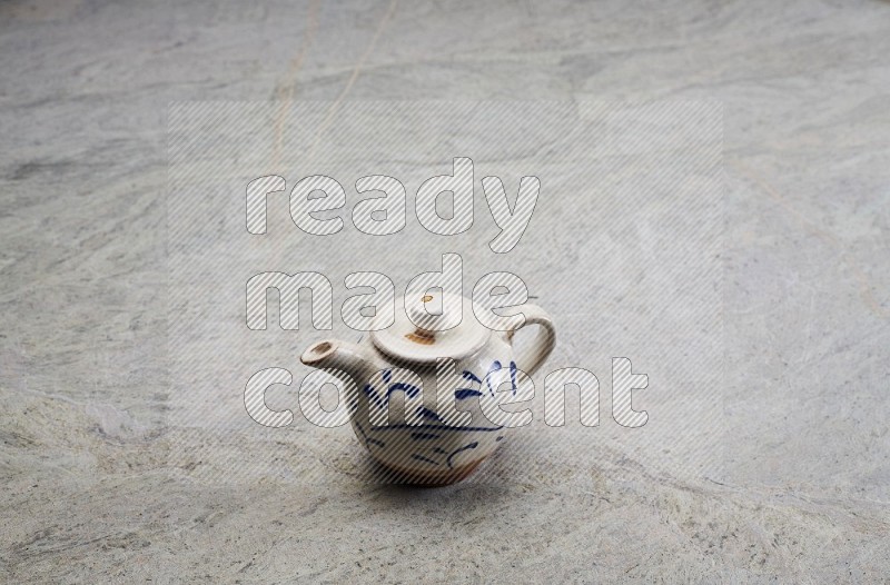 A Pottery Teapot On Grey Marble Flooring