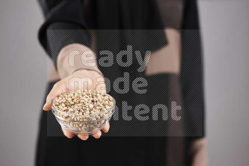 Woman in abaya holding different kinds of legumes in different positions