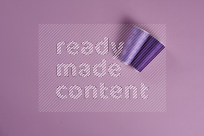 A purple and pink collection of sewing and tailoring tools arranged on a pink background