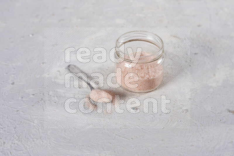 A glass jar full of fine himalayan salt on white background