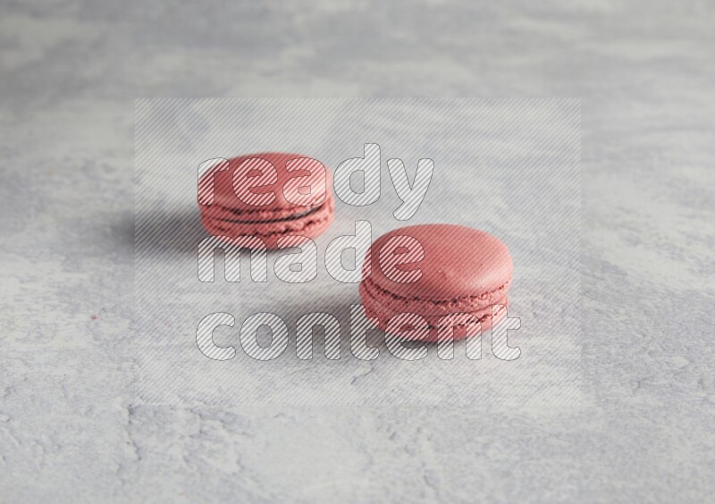 45º Shot of two Pink Raspberry macarons  on white  marble background