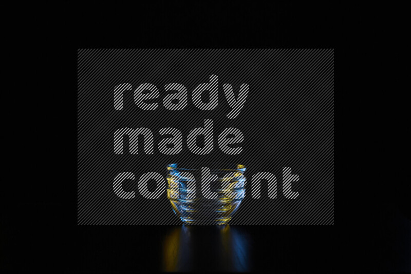 Glassware with rim light in blue and yellow against black background