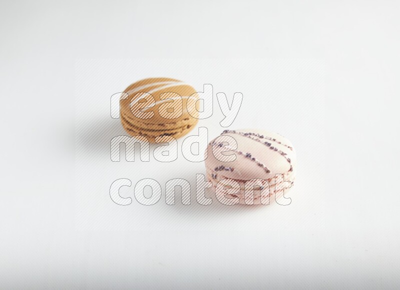 45º Shot of of two assorted Brown Irish Cream, and pink orange blossom macarons on white background