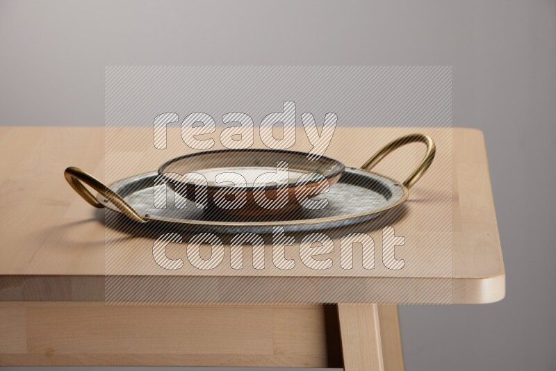 multicolored plate placed on a rounded stainless steel tray with golden handels on the edge of wooden table