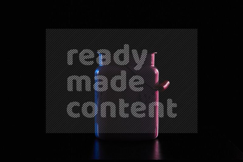 A vintage milk canister with colored rim light against black background