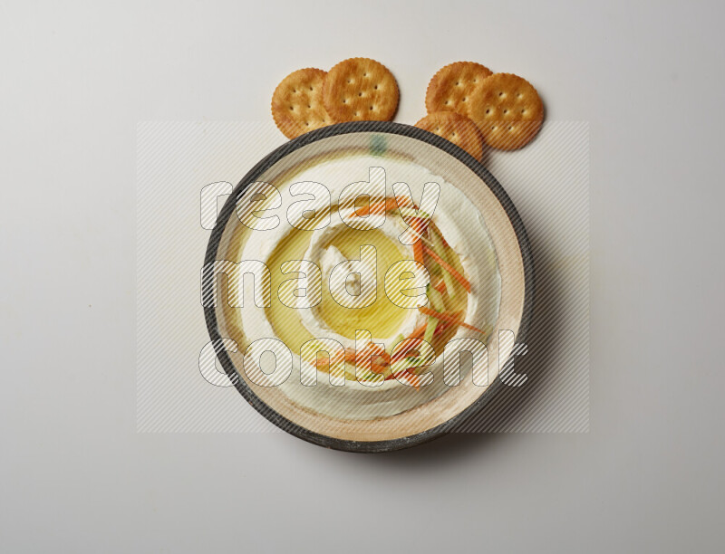 Lebnah garnished with sliced carrots &cucumber in a pottery plate on a white background