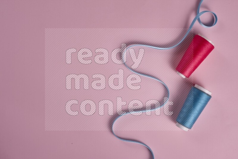 A blue collection of sewing and tailoring tools arranged on a pink background