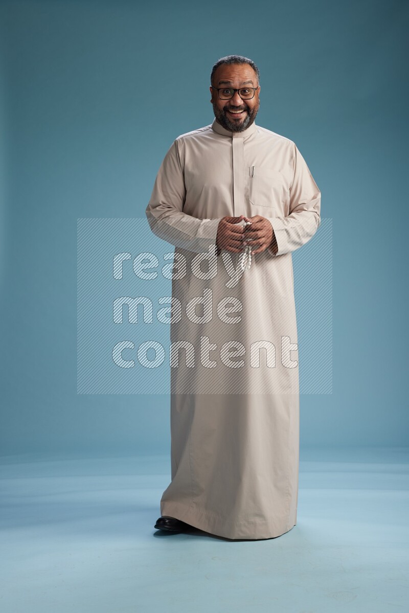 Saudi Man without shimag Standing Interacting with the camera on blue background