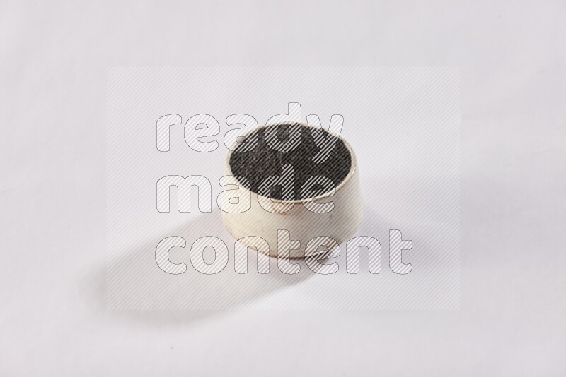 A beige pottery bowl full of black seeds on white flooring