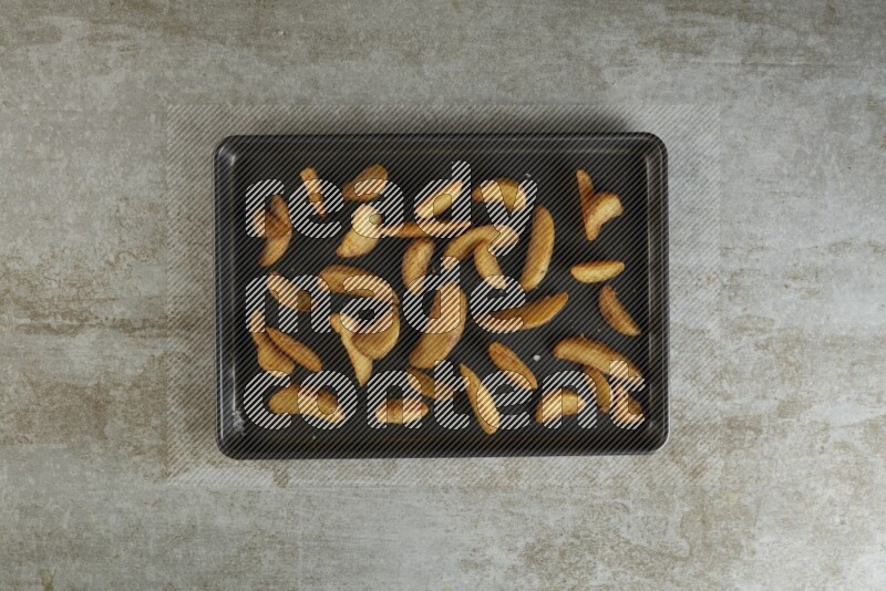 wedges potato in a black stainless steel rectangle tray on grey textured counter top