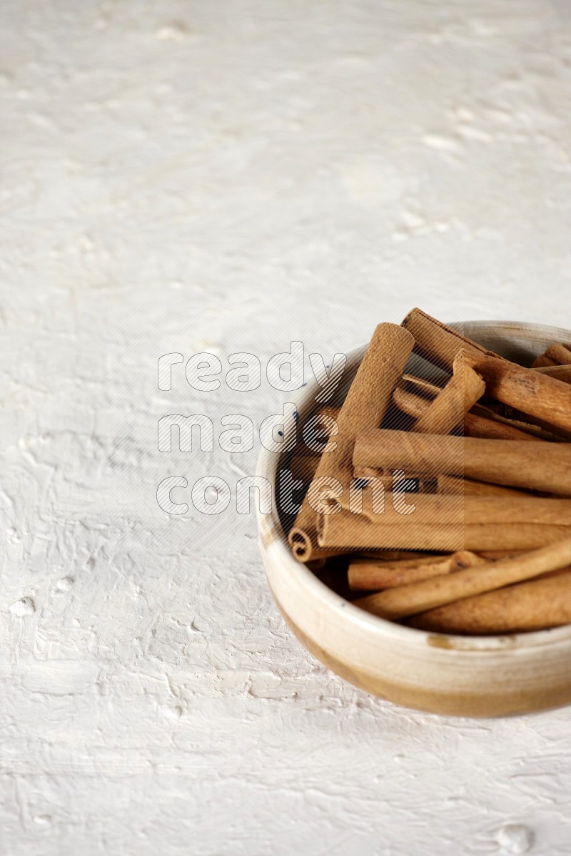 Cinnamon sticks in a ceramic bowl in different angles on white background