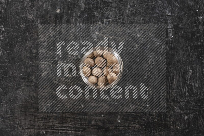 وعاء زجاجي ممتلئ بحبوب جوزة الطيب الكاملة علي خلفية سوداء