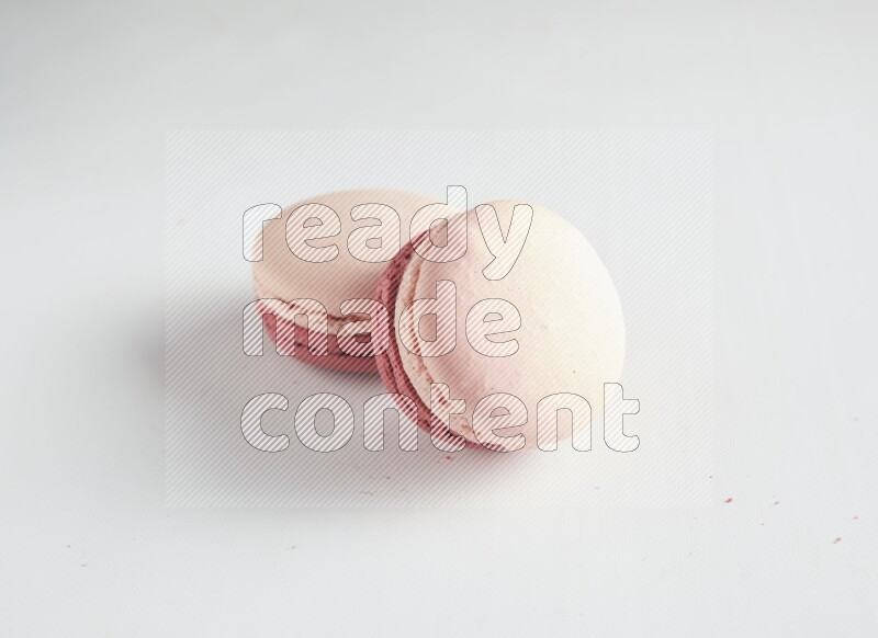 45º Shot of two Pink Litchi Raspberry macarons on white background