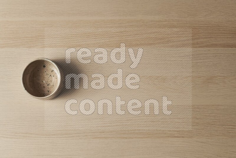 وعاء فخاري متعدد الألوان على خلفية خشبية فاتحة