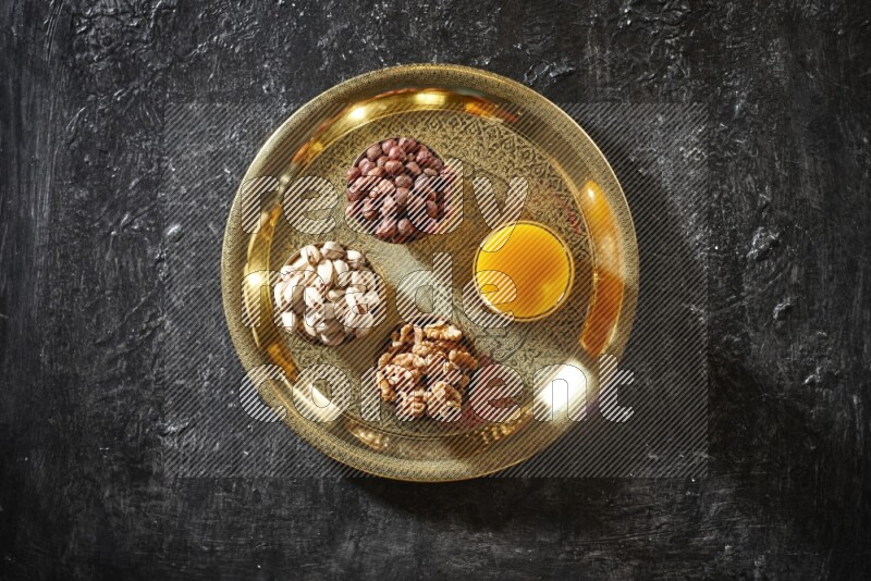 Nuts in metal bowls with qamar eldin on a tray in dark setup