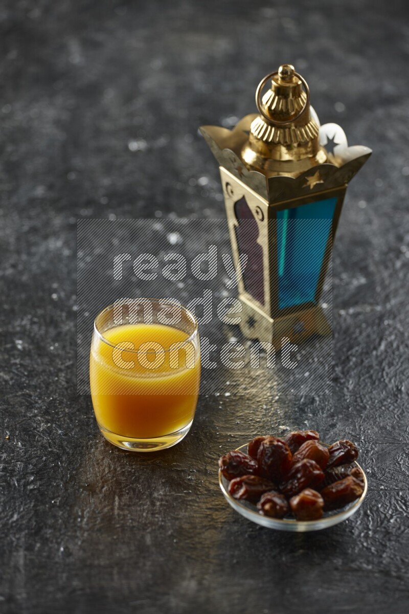 A golden lantern with different drinks, dates, nuts, prayer beads and quran on textured black background