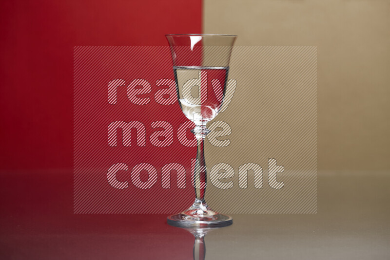 The image features a clear glassware filled with water, set against red and beige background