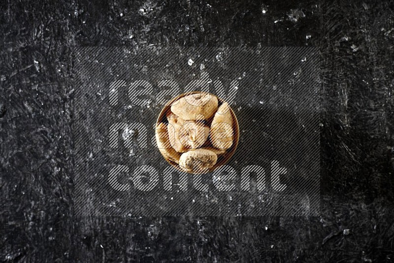 Dried fruits in a metal bowl in a dark setup