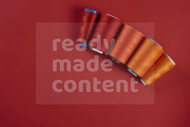 An orange collection of sewing and tailoring tools arranged on a red background