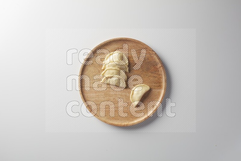 Five Sambosas on a wooden round plate on a white background