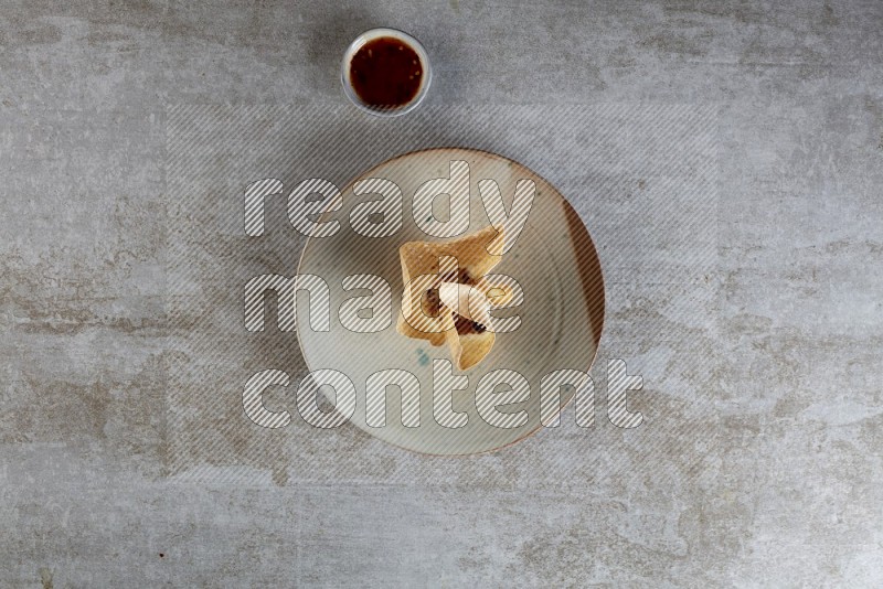 wonton cups with soy sauce ramkin on multi colored pottery on grey textured counter top