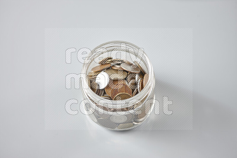 عملات معدنية قديمة عشوائية في وعاء زجاجي على خلفية رمادية
